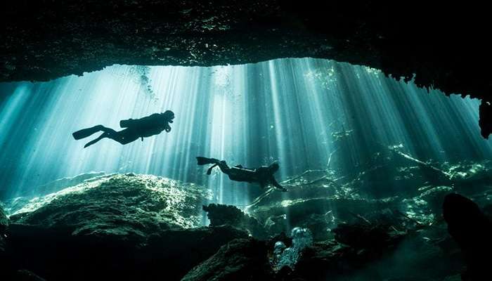 غواصان و پرتوهای نور در غار Eden Cenote 